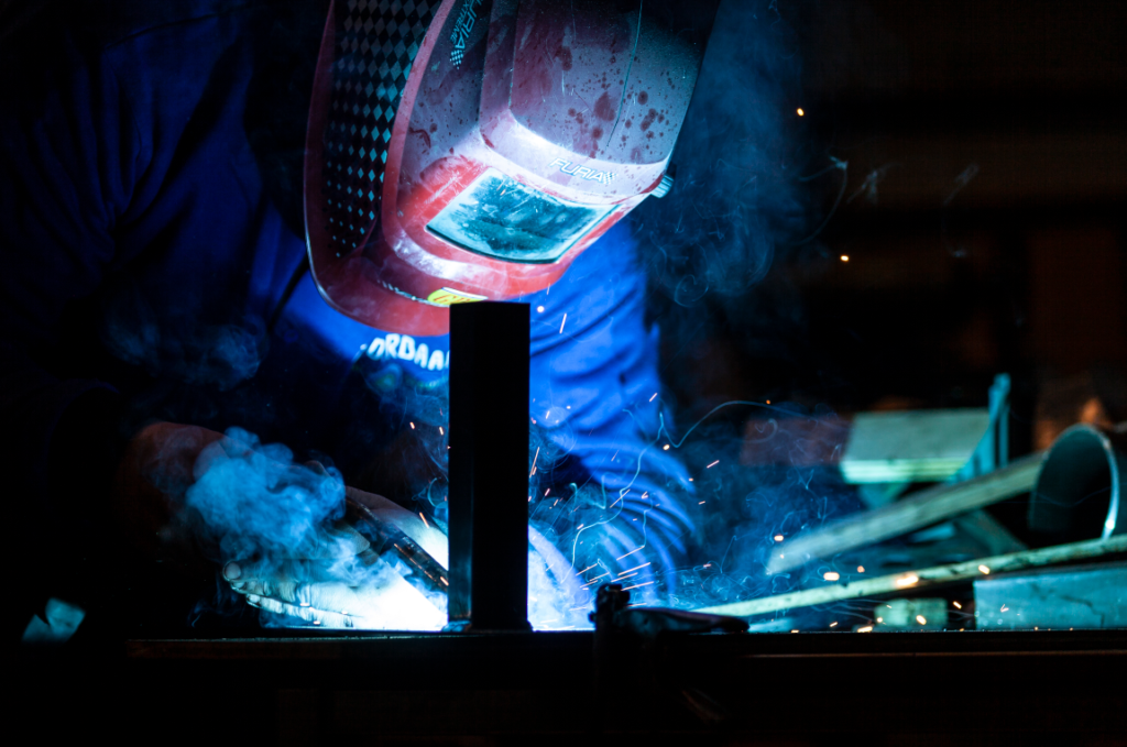 Professioneel MIG lassen van metalen constructie met automatische lashelm en beschermende uitrusting