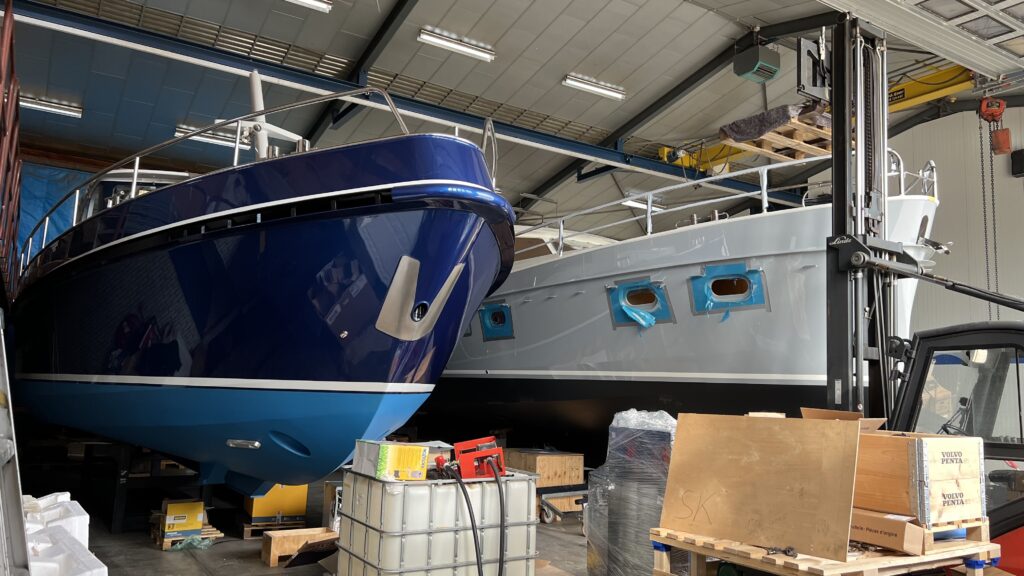 Scheepsonderhoud van blauwe boot in droogdok met materialen en apparatuur rondom het vaartuig