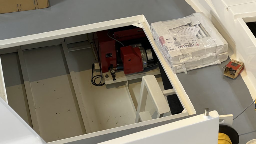 Onderhoudswerkzaamheden aan het interieur van een boot met open vloerpanelen en zichtbare technische installaties